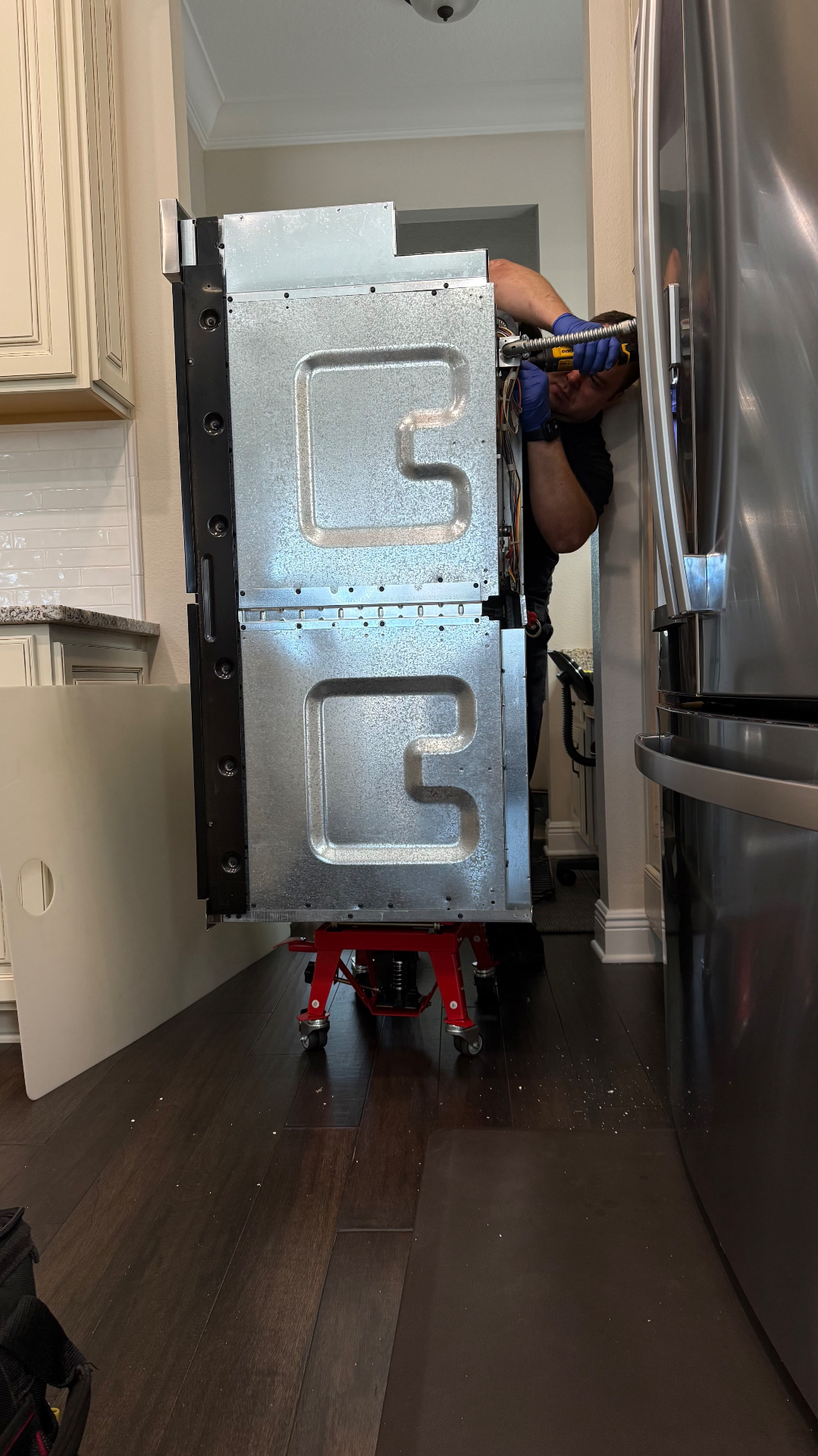 Technician working behind wall oven